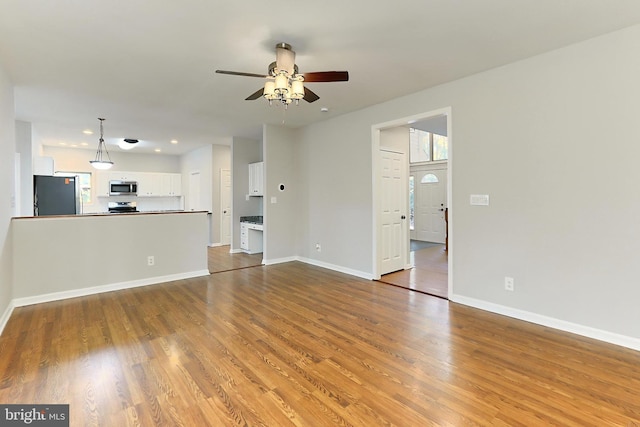 unfurnished living room with wood-type flooring and ceiling fan