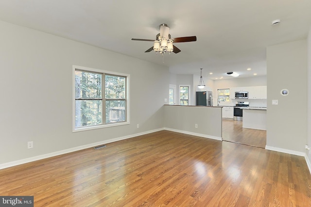 unfurnished living room featuring hardwood / wood-style flooring and ceiling fan