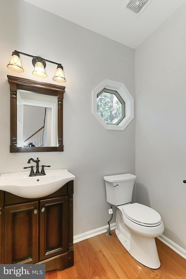 bathroom with hardwood / wood-style flooring, vanity, and toilet