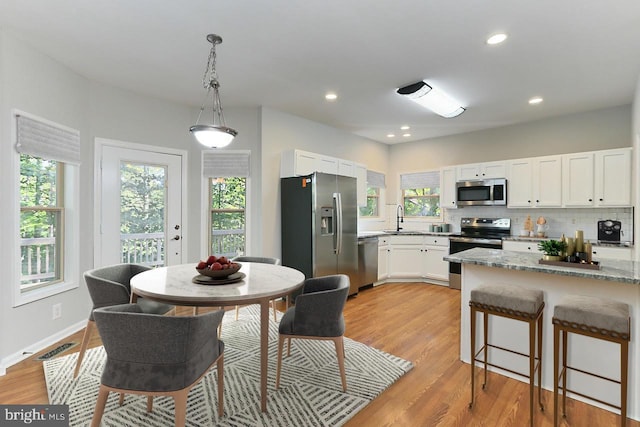 kitchen with sink, white cabinetry, appliances with stainless steel finishes, light stone countertops, and backsplash