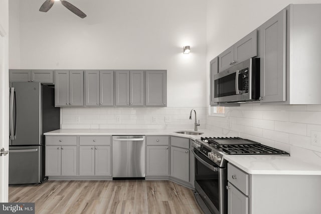 kitchen with stainless steel appliances, gray cabinets, light hardwood / wood-style floors, and sink