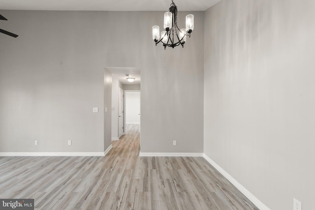 unfurnished dining area featuring ceiling fan with notable chandelier and light wood-type flooring