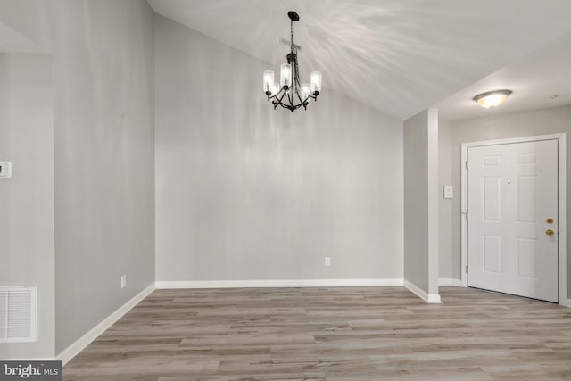 interior space featuring lofted ceiling, a notable chandelier, and light hardwood / wood-style floors