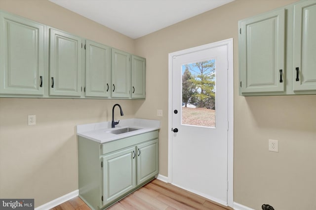 clothes washing area featuring sink, cabinets, and light wood-type flooring