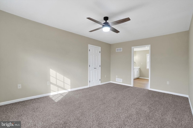 unfurnished bedroom featuring connected bathroom, light carpet, and ceiling fan