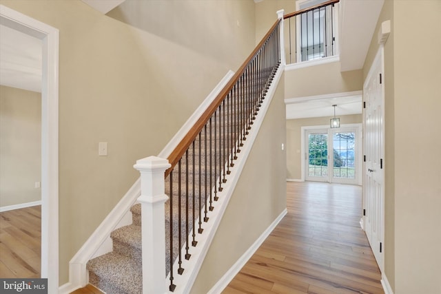 staircase featuring a towering ceiling and hardwood / wood-style floors