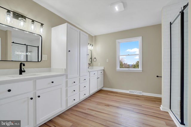 bathroom with wood-type flooring, vanity, and a shower with shower door