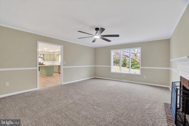 unfurnished living room featuring ceiling fan, ornamental molding, carpet flooring, and a brick fireplace