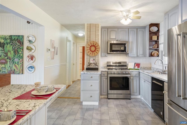 kitchen featuring sink, gray cabinetry, ceiling fan, stainless steel appliances, and backsplash