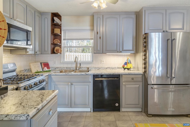 kitchen with sink, appliances with stainless steel finishes, gray cabinetry, backsplash, and light stone counters