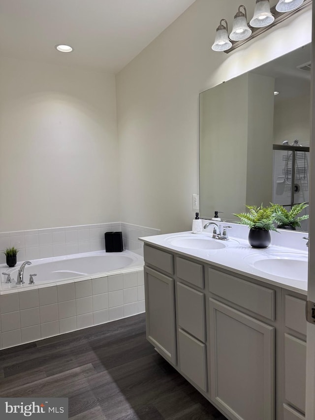 bathroom with vanity, tiled bath, and hardwood / wood-style floors