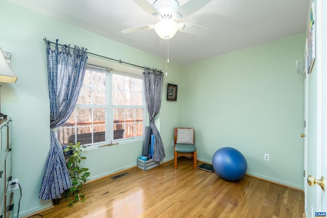 exercise room with ceiling fan and light wood-type flooring