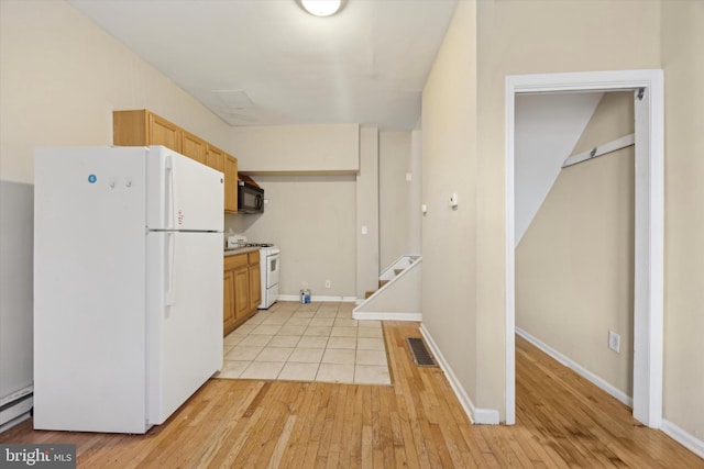 kitchen featuring white appliances, light hardwood / wood-style floors, baseboard heating, and light brown cabinets