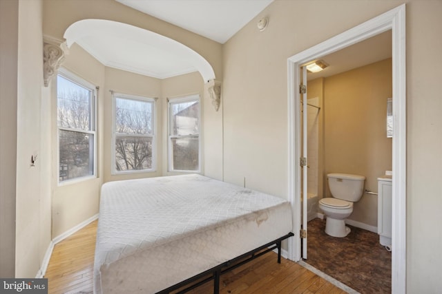 bedroom with connected bathroom and hardwood / wood-style floors