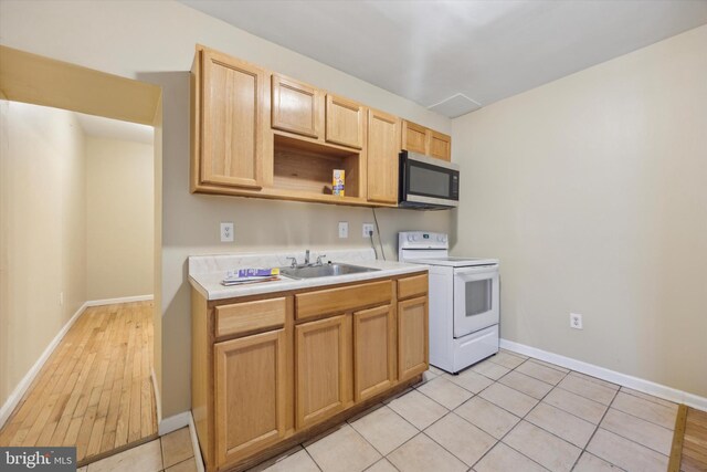 kitchen with light brown cabinetry, sink, electric range, and light tile patterned floors