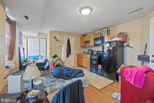 bedroom with black refrigerator, a closet, and light wood-type flooring