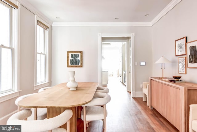 dining space with crown molding, plenty of natural light, and light hardwood / wood-style floors