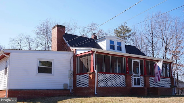 back of property with roof with shingles, a chimney, and a sunroom