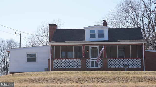 rear view of house featuring a sunroom, roof with shingles, and a chimney