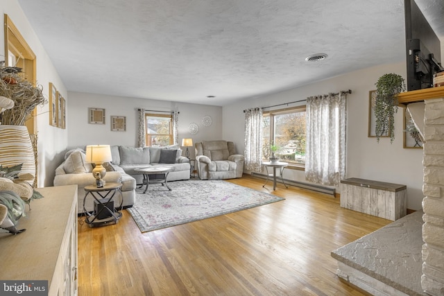 living room with a baseboard radiator, a healthy amount of sunlight, and light wood-type flooring