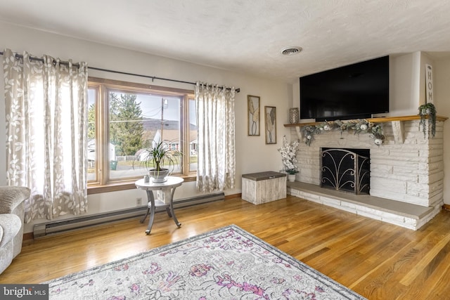 living room with a baseboard radiator, wood-type flooring, and a textured ceiling