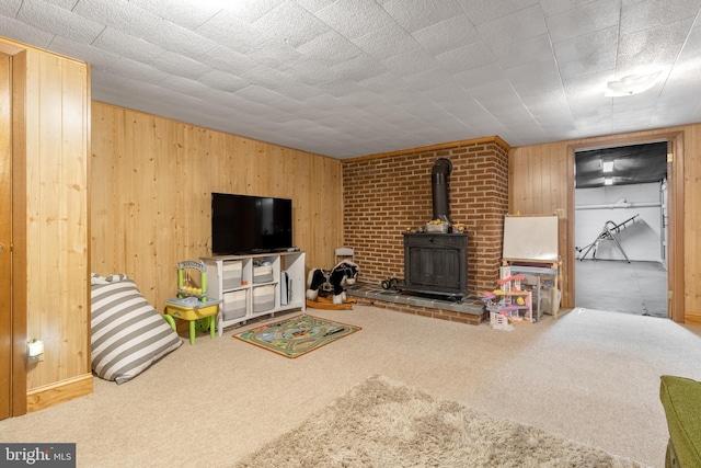 carpeted living room with a wood stove and wooden walls