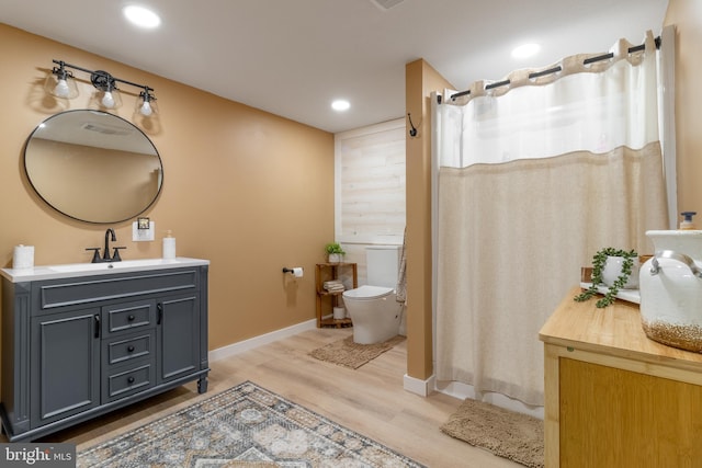 bathroom featuring wood-type flooring, toilet, and vanity