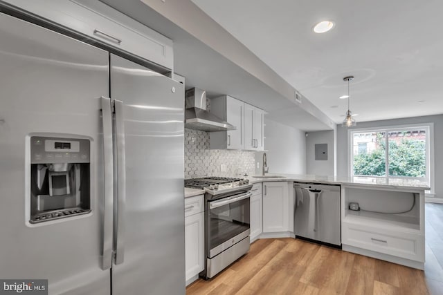 kitchen featuring wall chimney range hood, sink, white cabinetry, backsplash, and stainless steel appliances