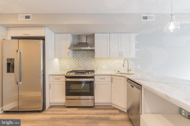 kitchen featuring wall chimney exhaust hood, white cabinetry, stainless steel appliances, and sink