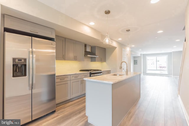 kitchen featuring decorative light fixtures, gray cabinets, stainless steel appliances, and wall chimney exhaust hood