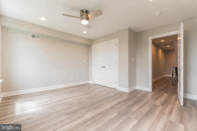 unfurnished bedroom with ceiling fan, light wood-type flooring, and a closet