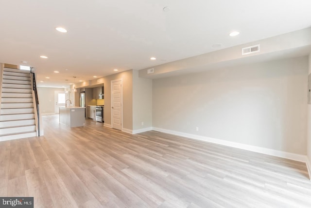 unfurnished living room with sink and light hardwood / wood-style floors