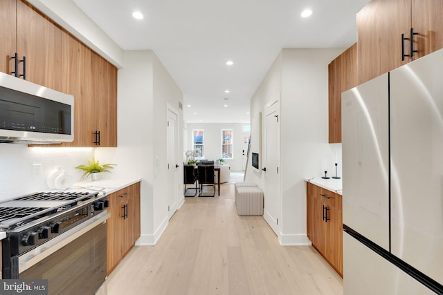 kitchen with appliances with stainless steel finishes, radiator, decorative backsplash, and light wood-type flooring