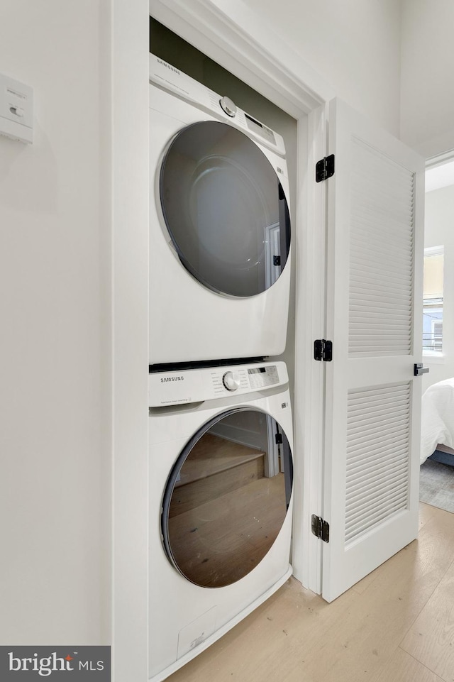 clothes washing area featuring stacked washer / drying machine and light hardwood / wood-style floors