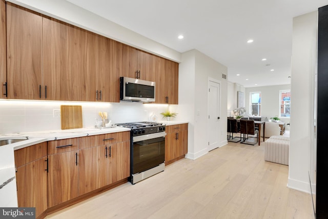 kitchen with gas range, tasteful backsplash, and light wood-type flooring