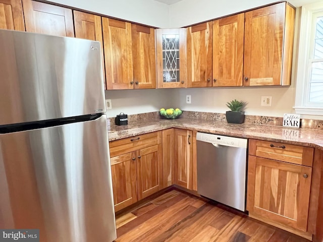 kitchen featuring stainless steel appliances, hardwood / wood-style flooring, and light stone counters