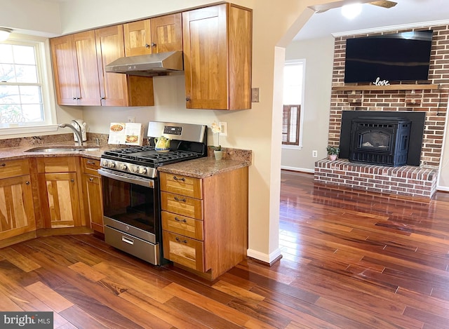 kitchen with gas stove, sink, dark wood-type flooring, and light stone counters