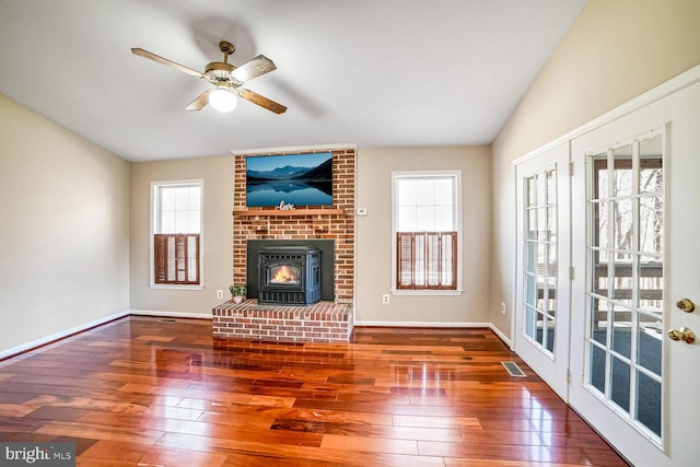 unfurnished living room with dark wood-type flooring, a wood stove, and ceiling fan