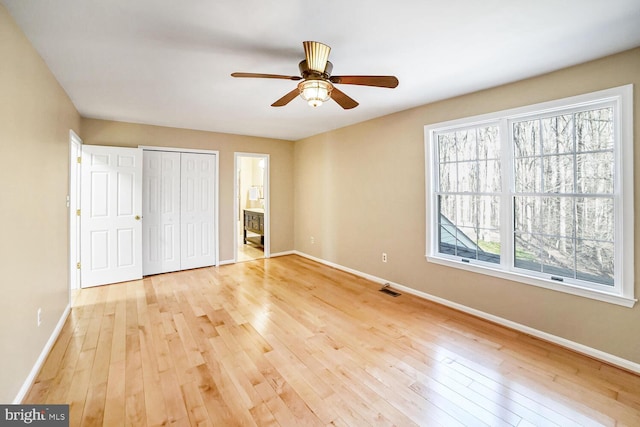 unfurnished bedroom featuring light hardwood / wood-style flooring, a closet, ceiling fan, and ensuite bathroom