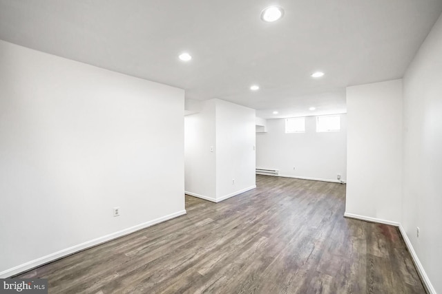 unfurnished room with a baseboard heating unit and dark hardwood / wood-style floors