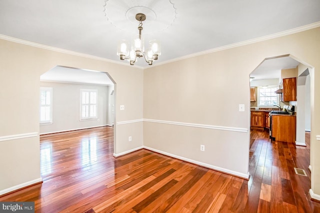 unfurnished room with hardwood / wood-style flooring, crown molding, and a chandelier