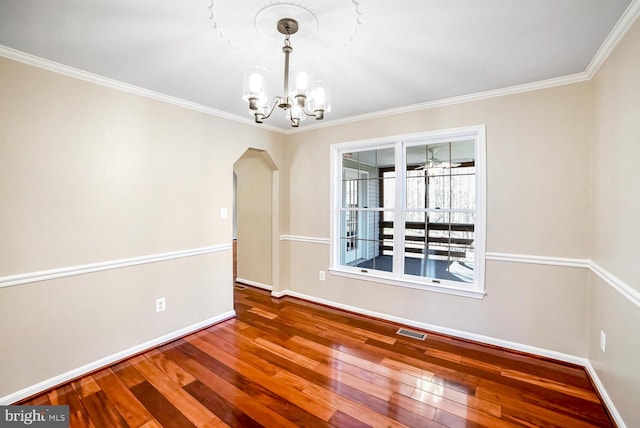 empty room featuring an inviting chandelier, ornamental molding, and hardwood / wood-style floors