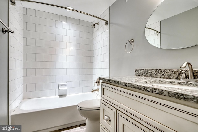 full bathroom featuring tiled shower / bath, vanity, and toilet