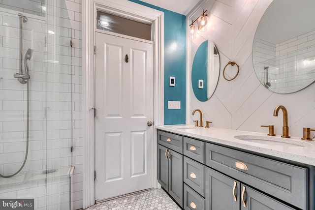 full bathroom with tiled shower, a sink, and double vanity