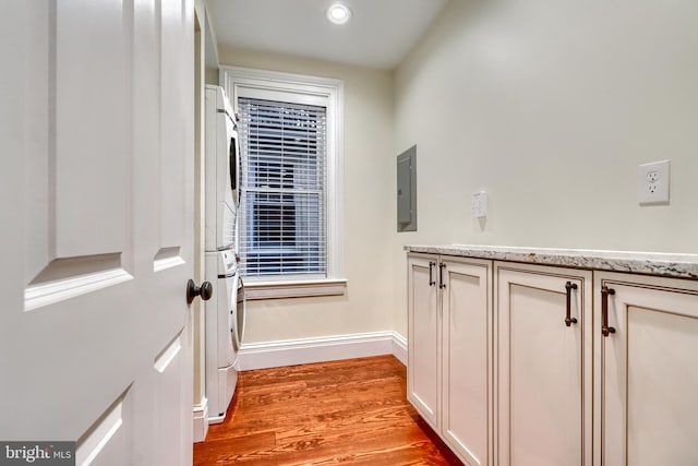 entryway featuring light hardwood / wood-style floors, stacked washer and clothes dryer, and electric panel