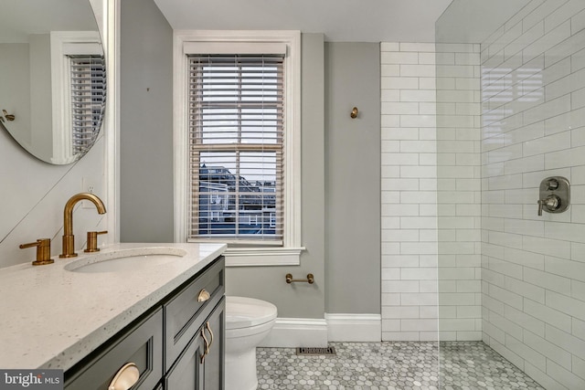 bathroom with vanity, toilet, and a tile shower