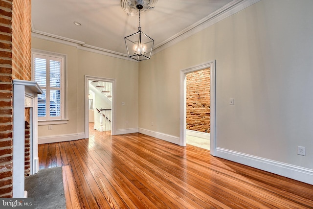 interior space with crown molding, brick wall, a chandelier, and light hardwood / wood-style floors