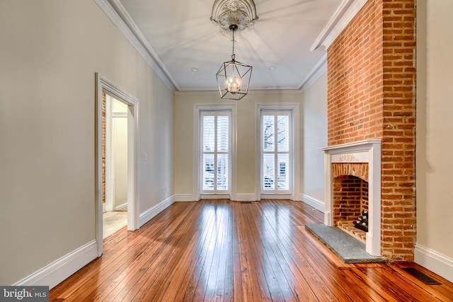 unfurnished living room featuring wood-type flooring, visible vents, ornamental molding, and baseboards