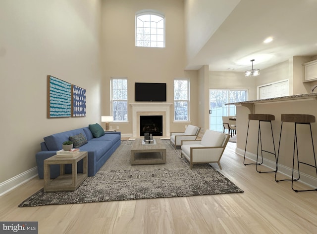 living room featuring a towering ceiling, a wealth of natural light, and light hardwood / wood-style flooring