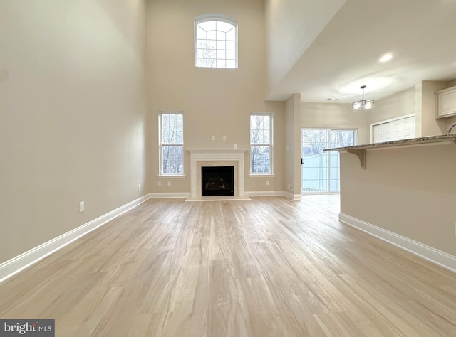 unfurnished living room with light hardwood / wood-style floors and a high ceiling